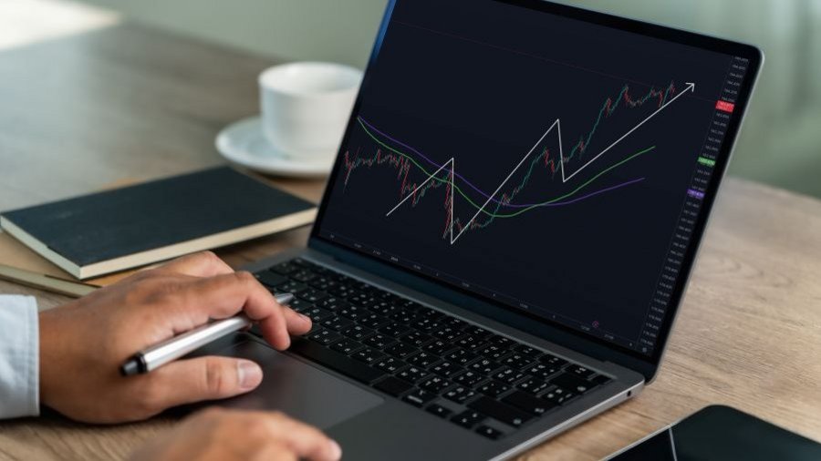 Neistota na trhoch Osoba pracuje na notebooku so zobrazeným grafom vývoja finančných trhov a trendových línií.