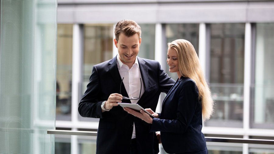 Rozbehnite s nami svoju kariéru Muž a žena v business oblečení sa rozprávajú na chodbe v kancelárii